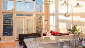 A modern kitchen with a granite countertop, stainless steel sink, and a ceiling fan. - One Bedroom Hideaway w/ free parking steps to Downtown (Raleigh)
