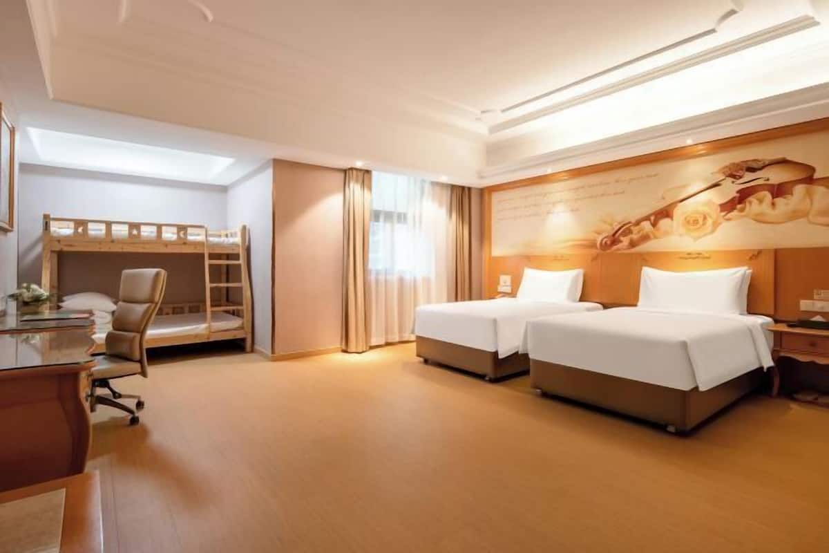 Ein Hotelzimmer mit zwei Betten, einem Schreibtisch, einem Stuhl und einem Schlafplatz.
