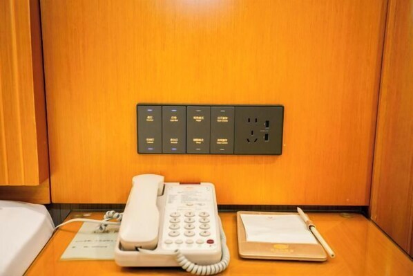A hotel room with a telephone, a notepad, and a pen on a wooden table.