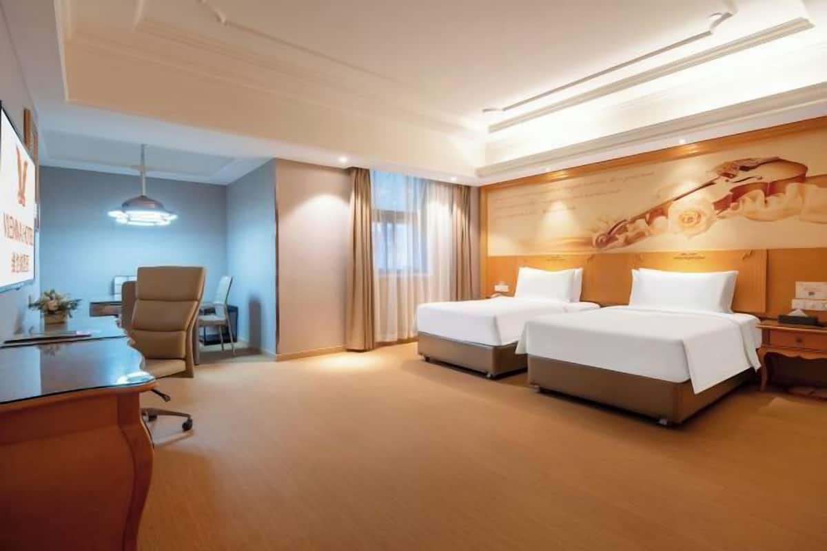 Ein Hotelzimmer mit zwei Betten, einem Schreibtisch, einem Stuhl und einem großen Fenster.