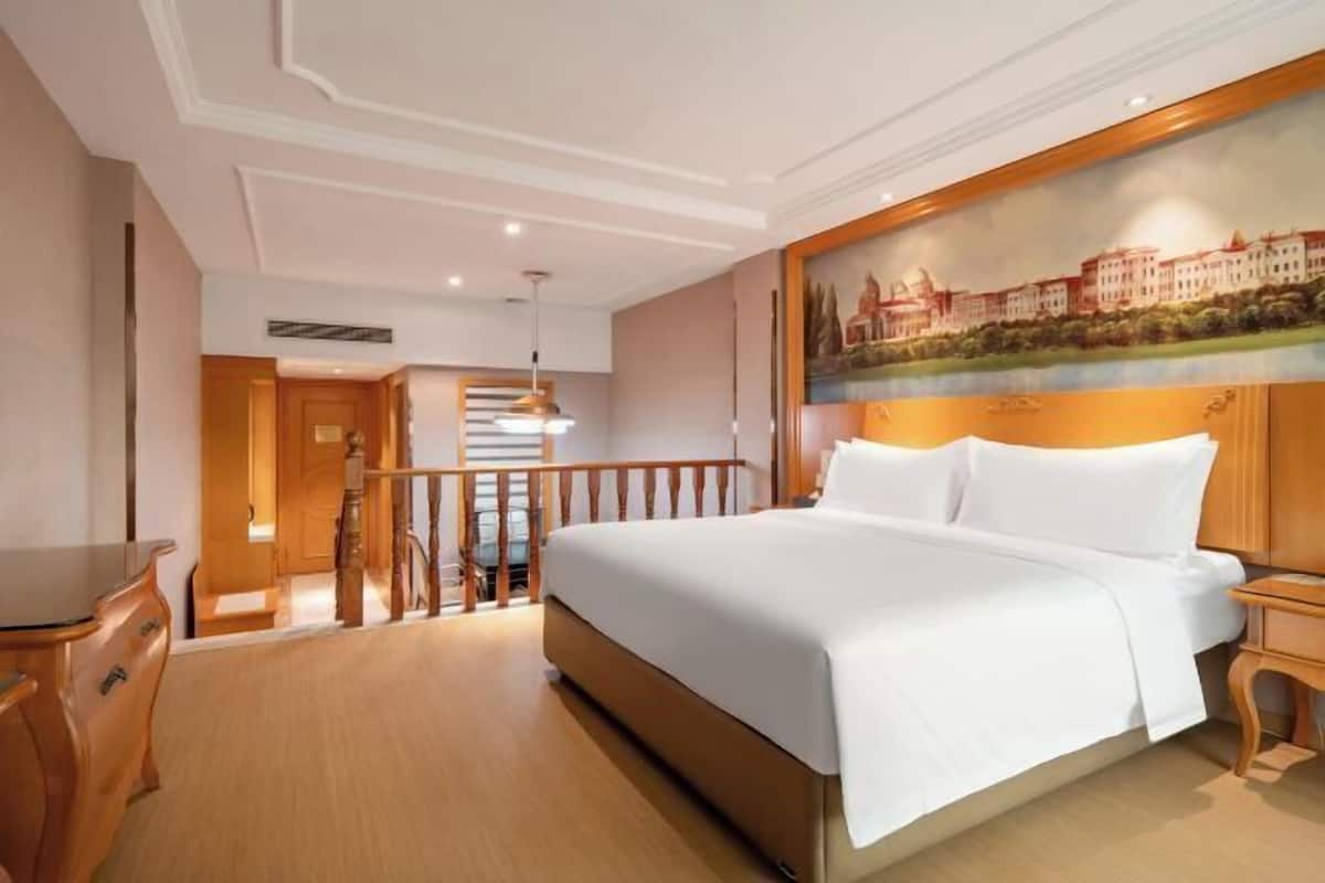 Ein Hotelzimmer mit einem großen Bett, Holzmöbeln, einem Bild an der Wand und einem Balkon.