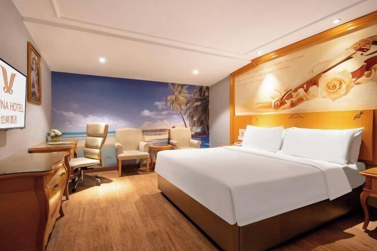 Ein Hotelzimmer mit einem großen Bett, einem Schreibtisch, zwei Stühlen und einem Wandbild.