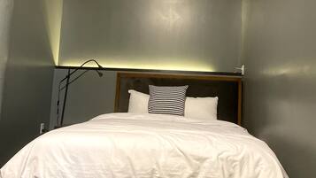 Un lit dans une chambre, avec une tête de lit, un oreiller blanc et un autre oreiller à motifs.