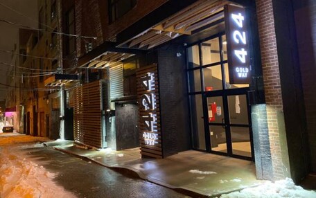A building with a large illuminated number '424' sign, a metal awning, and a brick facade.