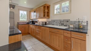 A modern kitchen with wooden cabinets, a black countertop, and a patterned backsplash. - House (Chémery)