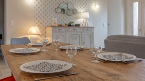 A dining table set with plates, glasses, and cutlery, a lamp, and a decorative mirror on a wall with a tufted pattern. - House (Chémery)