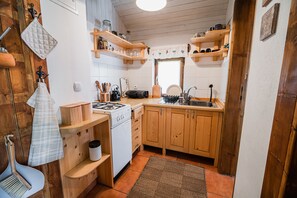 Eine kleine Küche mit Holzausstattung, einem weißen Herd und einem kleinen Fenster.