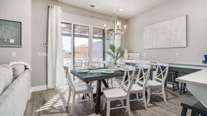 Un comedor moderno con una mesa grande, sillas blancas y una lámpara de araña.