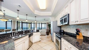 Una cocina moderna con encimeras de granito, armarios blancos y una isla grande.