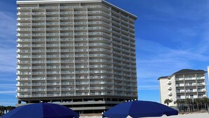 Et strandhotel med flere balkoner, liggestole og parasoller.