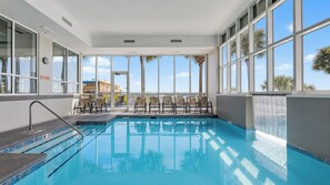 An indoor swimming pool with clear blue water, a no diving sign, and a waterfall feature.