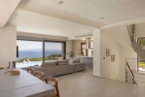 Un salon moderne avec un grand canapé, une table à manger et une vue sur la mer.