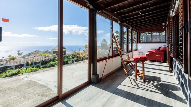 A spacious balcony with large glass doors, a wooden ceiling, and a red sofa. - Panoramic views and ideal area to rest and see the island of La Palma (Villa de Mazo)