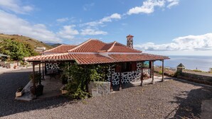 A gazebo with a tiled roof and stone walls, surrounded by gravel and potted plants, overlooking a coastal view. - Panoramic views and ideal area to rest and see the island of La Palma (Villa de Mazo)