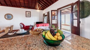 A dining area with a granite table, a bowl of fruit, and a red sofa. - Panoramic views and ideal area to rest and see the island of La Palma (Villa de Mazo)