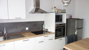 Una cocina moderna con armarios blancos, una campana extractora de acero inoxidable, un microondas, un horno y un refrigerador.