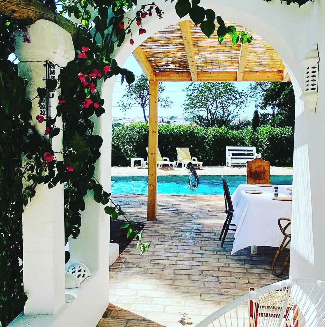 Ein Poolbereich im Freien mit einer Pergola, Liegestühlen und einem Essbereich.