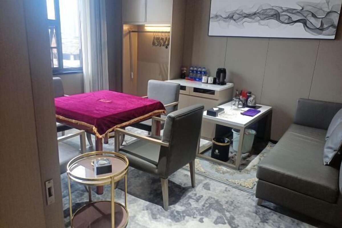 A compact hotel room with a bed, a desk, a chair, a sofa, and a small table.