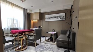 Une chambre d’hôtel comprenant un lit, un bureau, deux chaises, une table basse et une lampe sur pied.