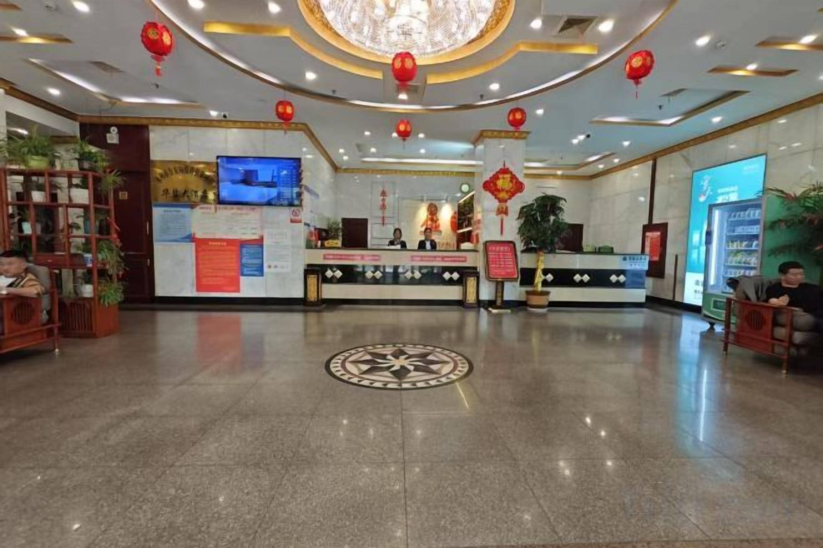 A hotel lobby with a reception desk, a television, and a large digital screen.