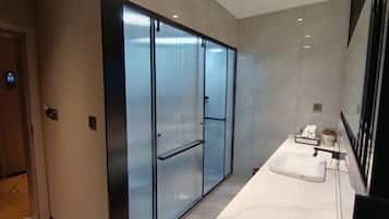 A modern bathroom with a large mirror, a white sink, and a glass-enclosed shower area.