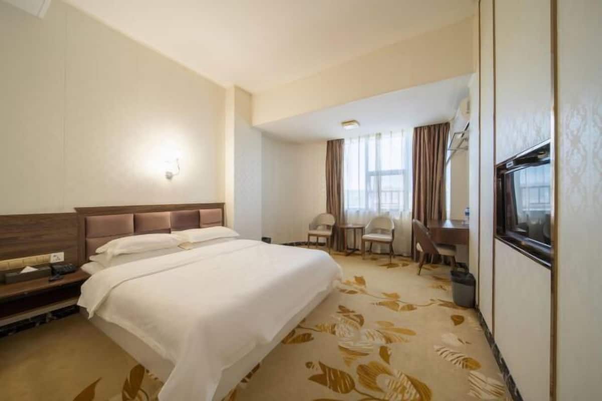 Una habitación de hotel con una cama, un escritorio y un televisor.