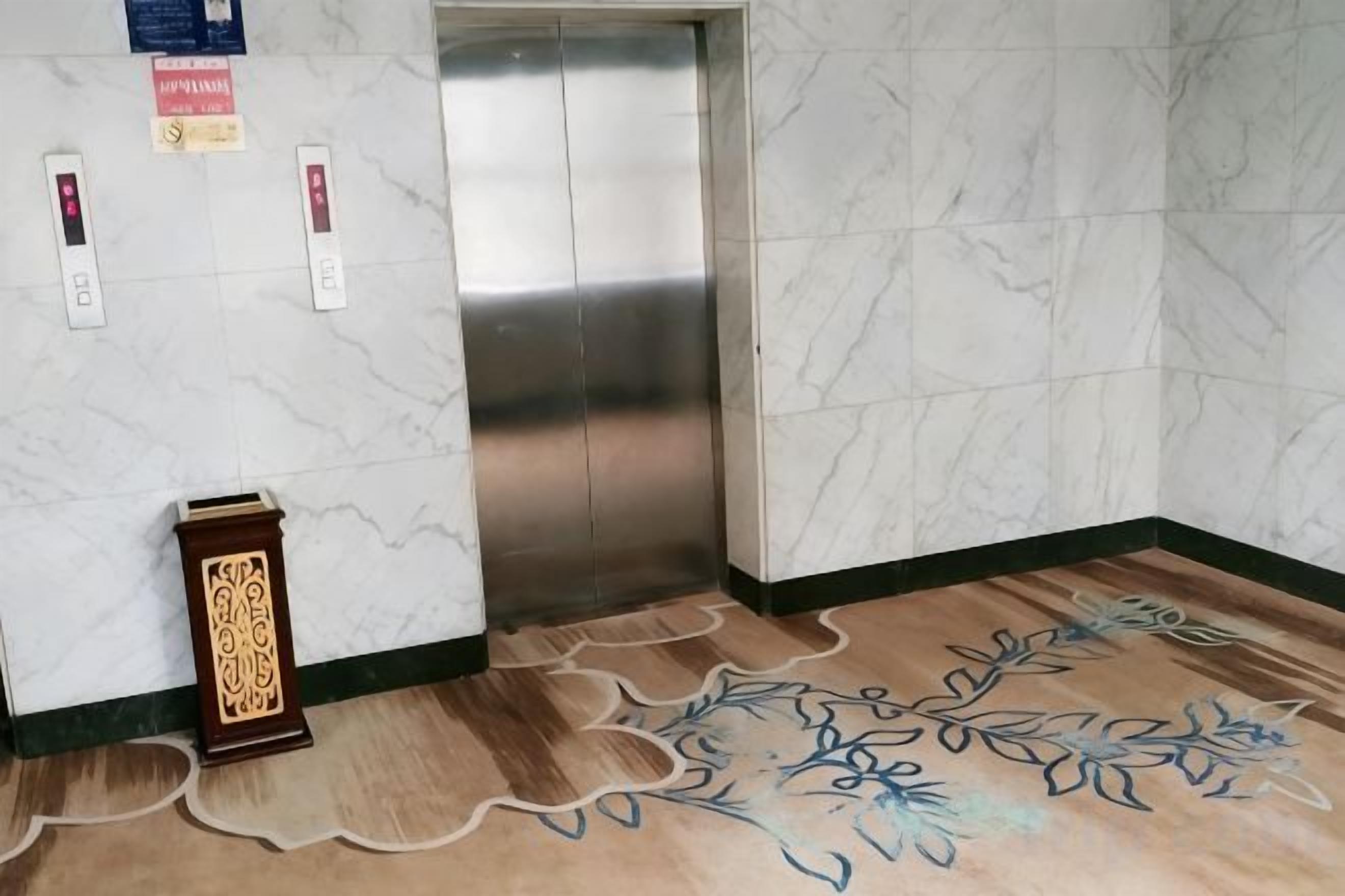 En elevator med en marmorvæg og et mønstret tæppe.