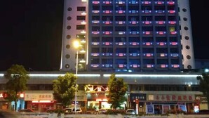 Un hôtel à plusieurs étages, doté de fenêtres illuminées et d’un restaurant situé au rez-de-chaussée.