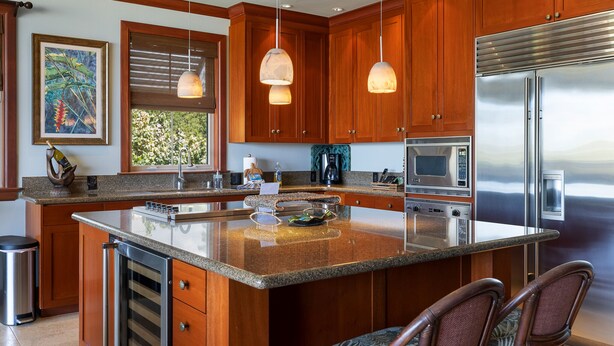 A modern kitchen with wooden cabinets, stainless steel appliances, and a large island with seating.