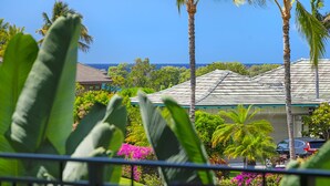 A view of a residential area with a house, palm trees, and a clear blue sky.