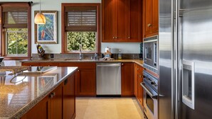 A modern kitchen with wooden cabinets, stainless steel appliances, and a large island.