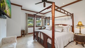 A four-poster bed with a wooden frame, a ceiling fan, and a nightstand with a lamp.
