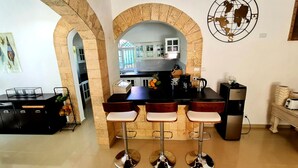 A kitchen with a central island, three bar stools, and a coffee machine. - Exclusive Luxury Getaway: 6 BRM Tropical Villa, Just 5 Minutes from Beaches (Sosúa)