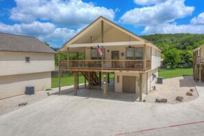 A two-story building with a balcony, a flag, and a view of a green landscape.