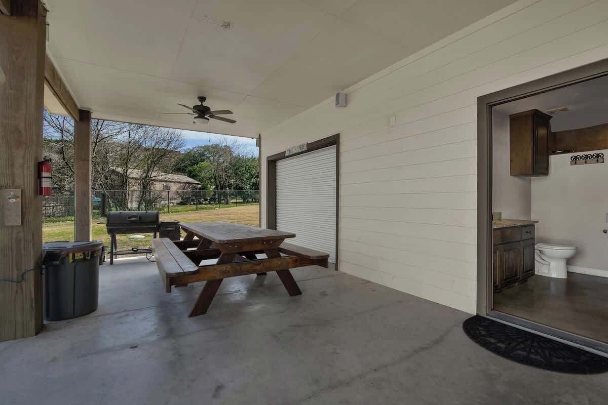 A covered patio with a picnic table, a ceiling fan, and a view of the backyard.
