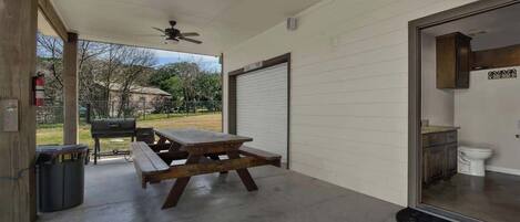 A covered patio with a picnic table, a ceiling fan, and a view of the backyard.