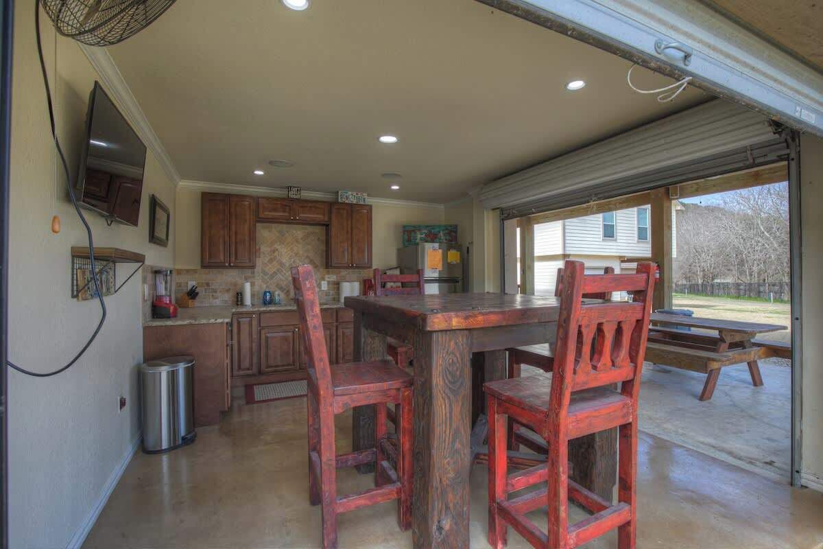 A kitchen with wooden cabinets, a large island, and a dining area with red chairs.