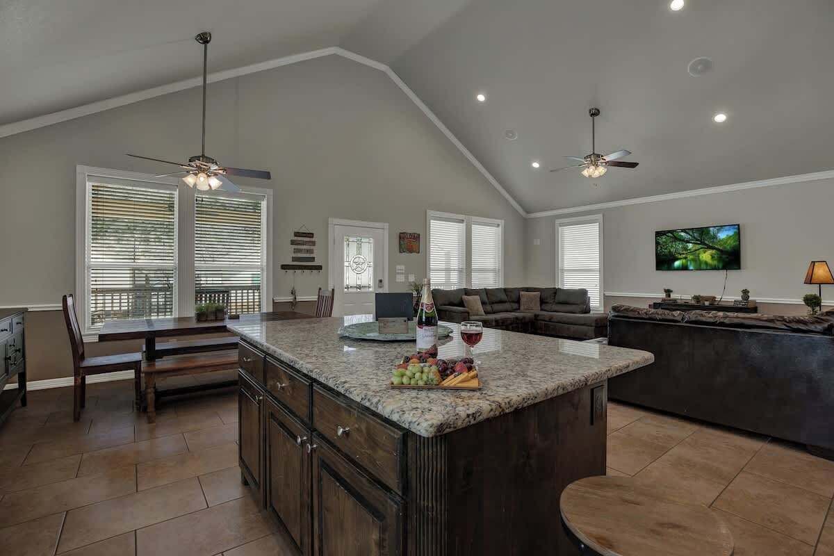Una cocina amplia con una isla grande, armarios de madera oscura y un comedor con mesa y sillas.