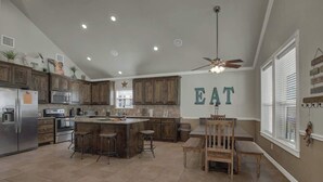 A spacious kitchen with a central island, wooden cabinets, and a ceiling fan. - Easy Tubing!-Right on the River! (New Braunfels)