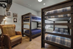 A room with bunk beds, a sofa, and a lamp.