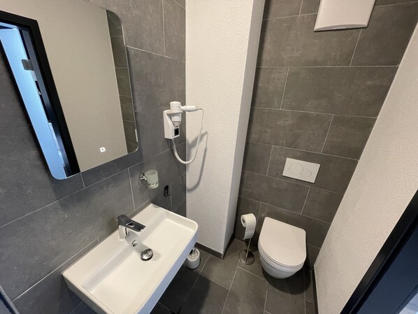 Un baño moderno con lavabo, espejo, inodoro y secador de pelo.