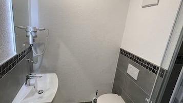 Une petite salle de bain avec un lavabo blanc, des toilettes et une douche à parois de verre.