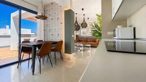 Eine moderne Küche mit Essbereich, einer Couch und Blick zum Himmel.