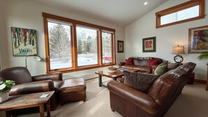 A spacious living room with leather furniture, large windows, and artwork on the walls. - JHRL - Eagles Rest 16 - Newly renovated, spacious townhome (Teton Village)