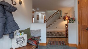 A hallway with a wooden bench, a coat rack, and a wall-mounted light fixture. - JHRL - Eagles Rest 16 - Newly renovated, spacious townhome (Teton Village)