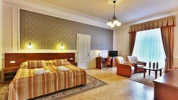 A hotel room with a large bed, a desk, a chair, a television, and a window with curtains.