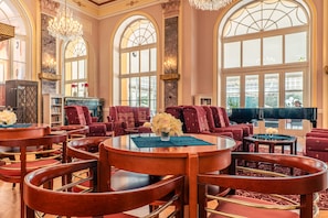 A luxurious lobby with high ceilings, arched windows, and elegant furniture. - Hotel Radium Palace (Jachymov)