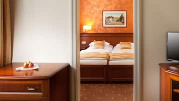 Une chambre d’hôtel avec un bureau en bois, une télévision et deux lits avec des oreillers assortis.
