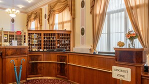 A bar area with a 'Discreet Zone' sign, wooden paneling, and a patterned carpet. - Hotel Radium Palace (Jachymov)