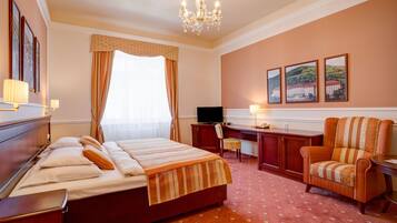 A hotel room with a bed, desk, chair, television, and artwork on the wall.